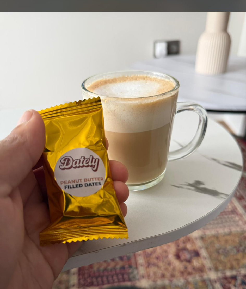 A gold DATELY® sample beside a cup of coffee